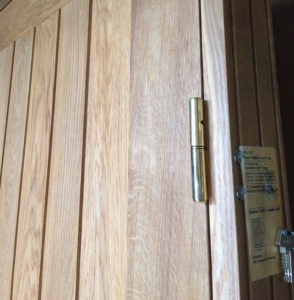 Special rammedør med ilagte lodrette planker udført i eg, døren er desuden beslået med messinghængsler.